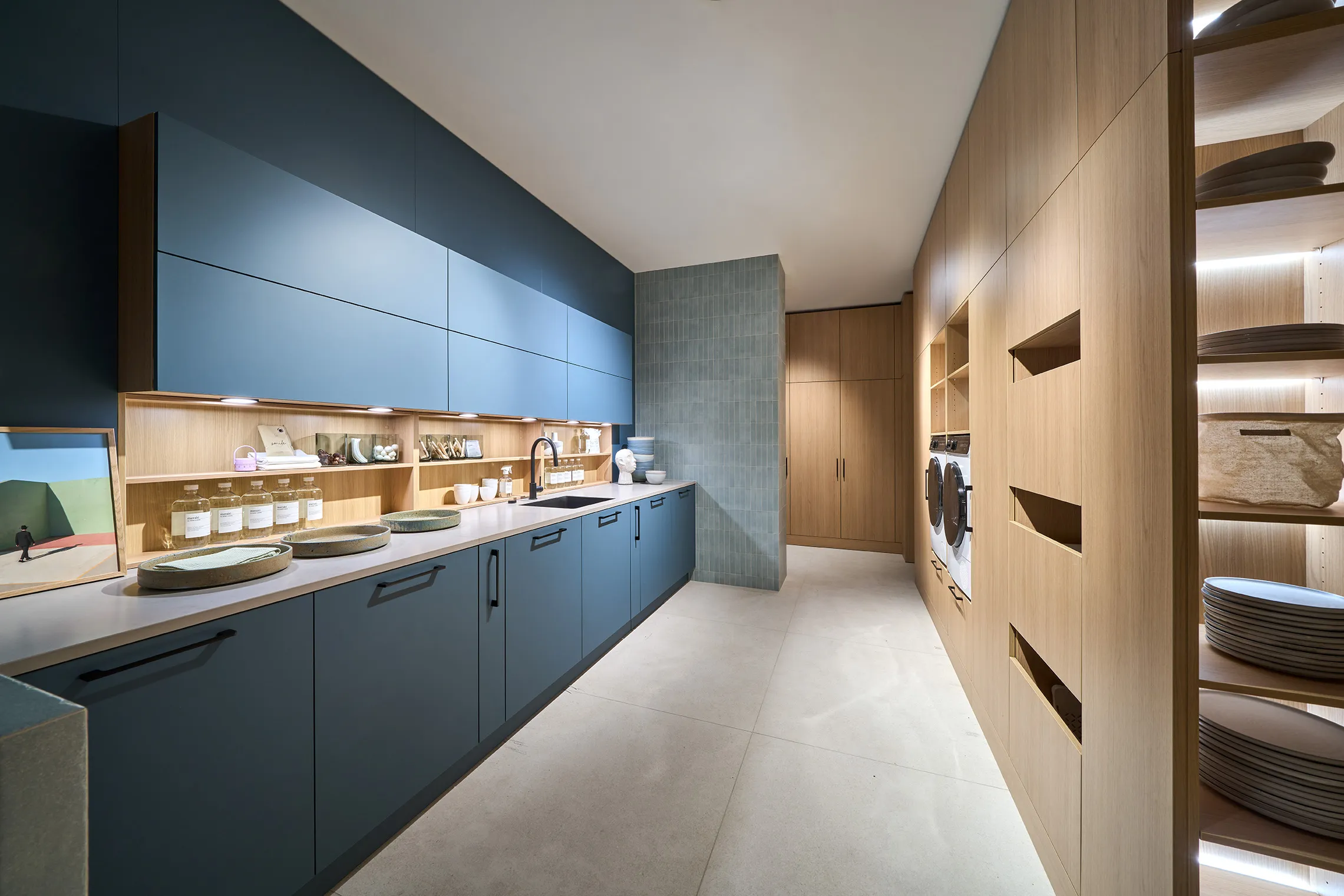 A dark Häcker Systemat kitchen with a veined splashback, in a room with an ornate plaster ceiling